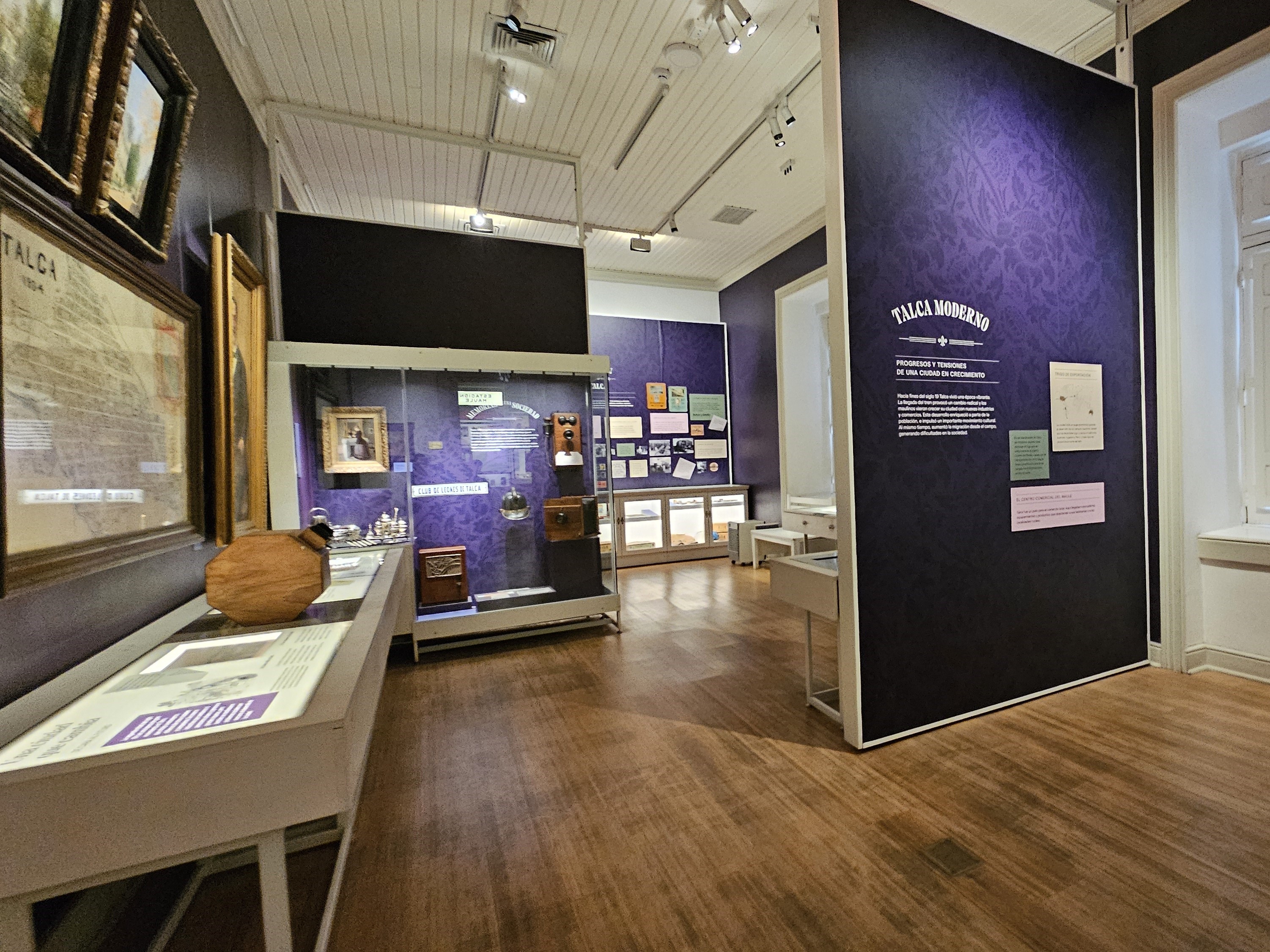Fotografía del interior del museo, donde se aprecian mesones que exponen información de talca, este sector del museo es de color azul